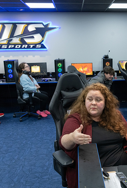 An instructor speaks to students sitting in gaming chairs in the Esports Arena.