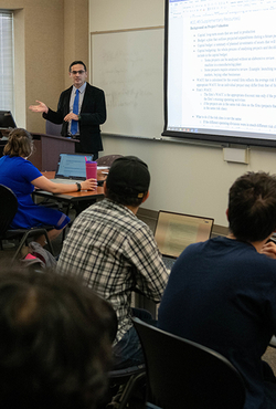 Students sitting at desks in a classroom as a professor teaches. 