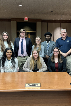 A group of Mock Trial students pose in a courtroom.