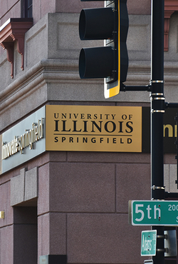 A building with a sign reading University of Illinois Springfield and a traffic light.