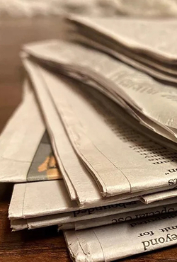 A stack of newspapers on a desk.