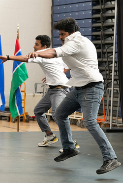 Two people in white shirts and jeans perform a synchronized dance on stage during a cultural event.