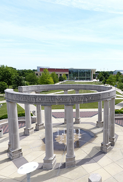 Circular stone pavilion with columns in a park setting.
