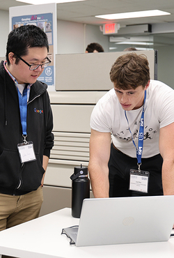 Two men collaborating at a laptop in an office setting.