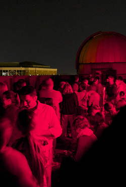 A large group of people on the roof of UIS Brookens Library at night with red lights.