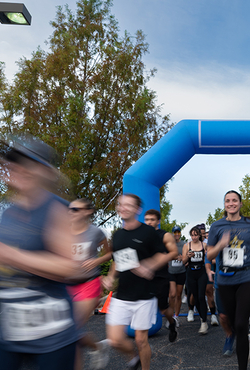 Runners passing a blue inflatable arch, blurred motion.