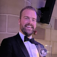 headshot of Luke Runyon holding an award