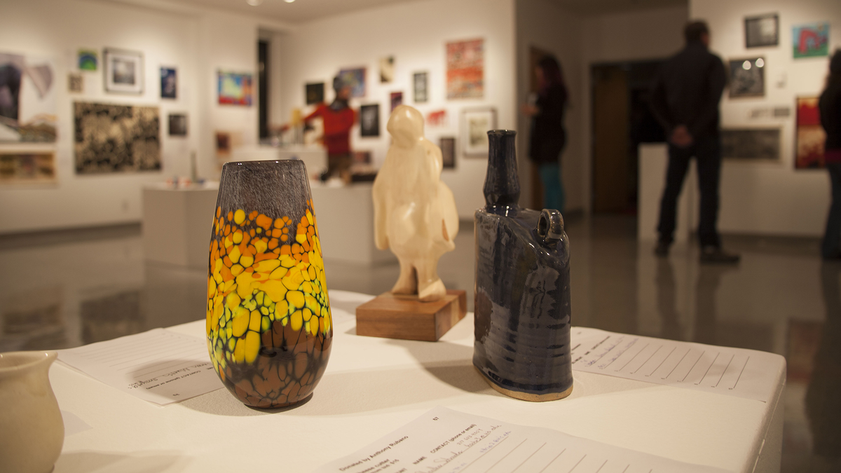 Vases and sculpture on display in a dimly lit art gallery.