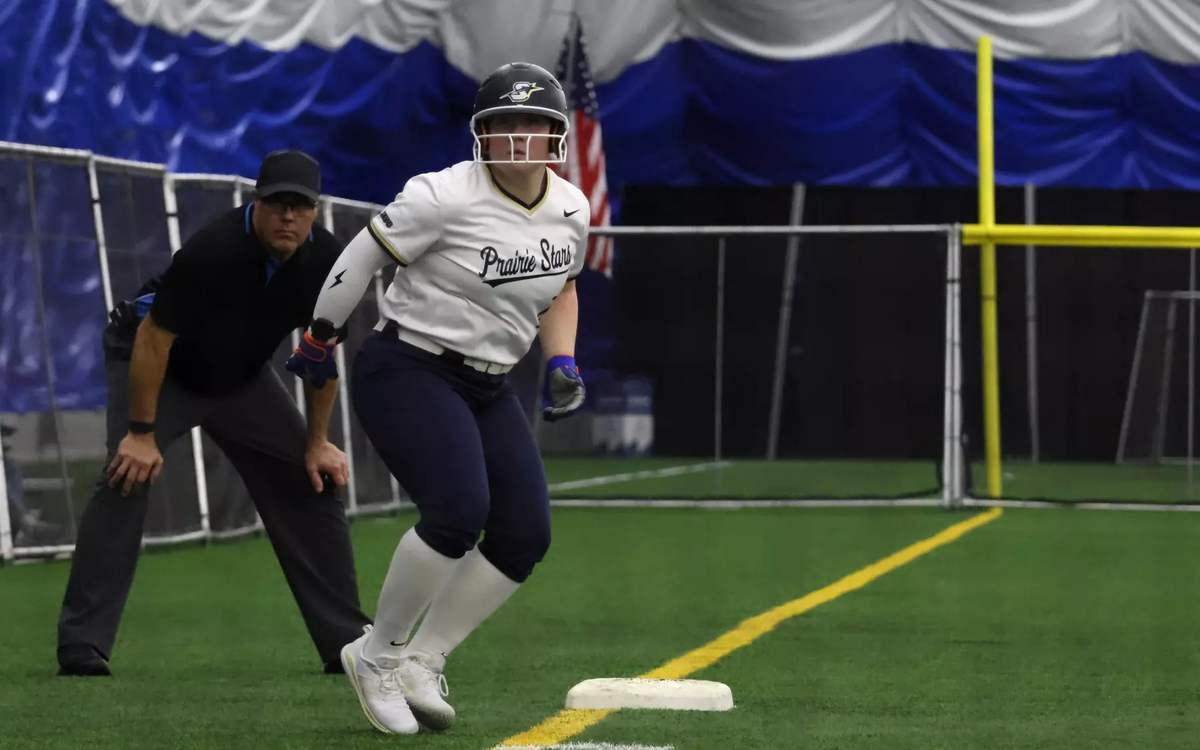 Emme Steward on third base at softball tournament in Springfield Clinic Dome, wearing white and blue UIS Prairie Stars uniform