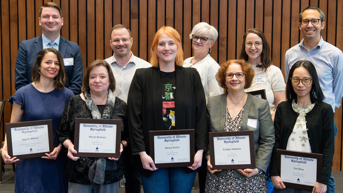 Ten faculty members pose for a photo holding their awards. 