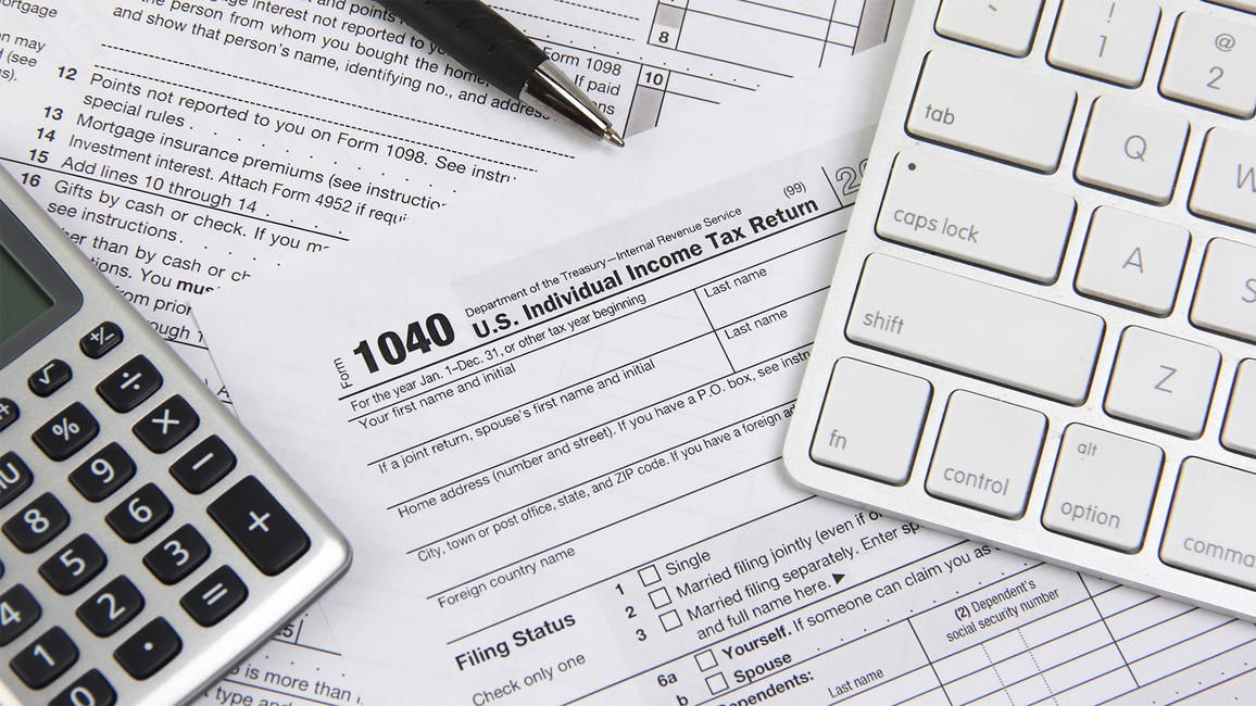 Tax forms with a calculator, pen, and keyboard.