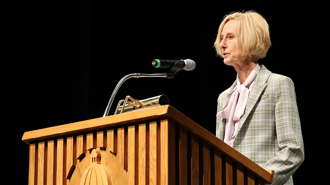 A woman speaks at a podium with a microphone.