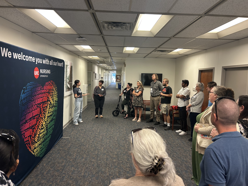 People gather in a hallway near a colorful mural and wall sign.