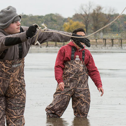 people standing in the water with camouflage overalls