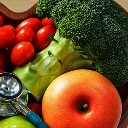 a stethoscope laying on top of a heart shaped bowl full of fruits and vegetables