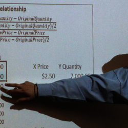 accounting professor pointing to formulas on the whiteboard