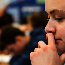 a student at their desk in a classroom looking down at a laptop