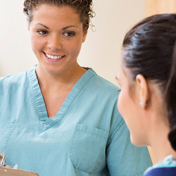 Nurse smiling at patient while holding a clipboard.