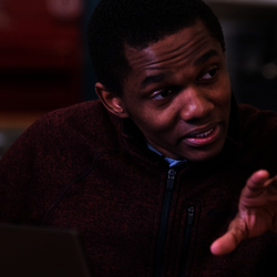 a student at his laptop explaining a concept to someone off-screen