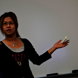 a female teacher speaking to the class in front of a white board