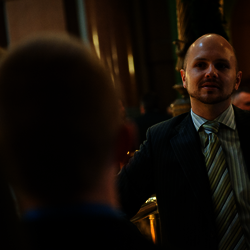 a man in a suit talking to others in a crowded business hall