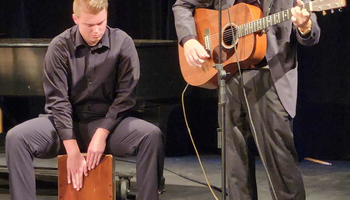 Photo of two musicians playing guitar and snare drum