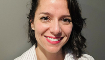 Smiling woman in a striped shirt against a gray background