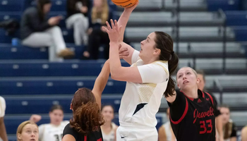 Brooke Spychalski playing basketball in white UIS uniform