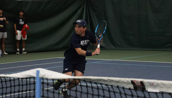 Pablo Herrera playing tennis in UIS blue in indoor facility