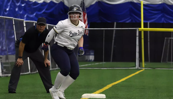 Emme Steward on third base at softball tournament in Springfield Clinic Dome, wearing white and blue UIS Prairie Stars uniform