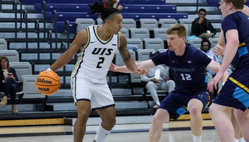 Jordan Rice playing basketball in white UIS uniform