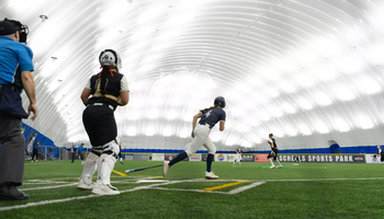 A photo of Bailey Masching and others running the bases at softball tournament in Scheels Sports Dome