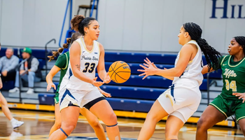 Allysia McDaniel and Kayla Rice playing basketball in white UIS uniforms