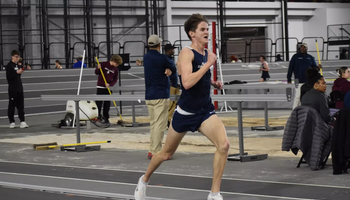 Ryan Kries running at an indoor track in blue UIS uniform
