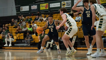 Jordan Rice playing basketball in blue UIS uniform in Missouri S&T gym