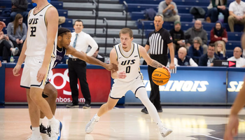 Britton Dutton playing basketball in white UIS uniform