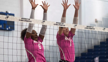 UIS volleyball block, pink jerseys