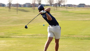 Julien Babineau playing golf in blue UIS polo