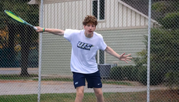 Kai Van-Roon playing tennis in white UIS uniform