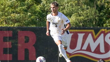 Adam Knaze playing soccer in white UIS uniform