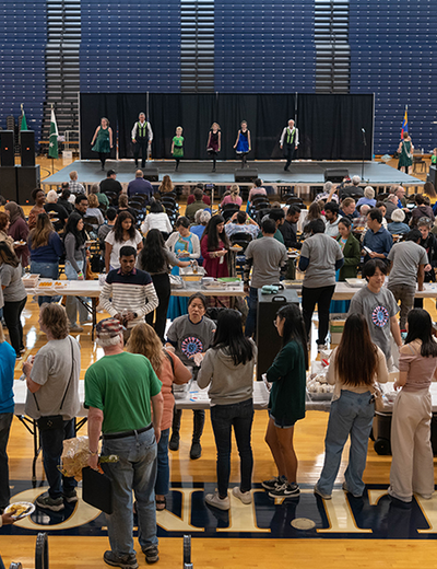 People line up for food as performances take place on stage.