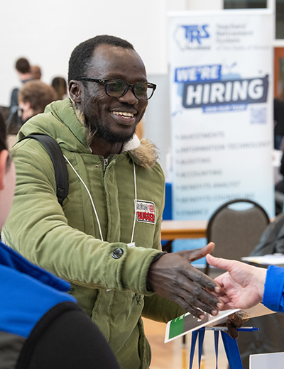 A student shakes hands with an employer at the 2024 UIS Career Connections Expo, networking for job and internship opportunities.