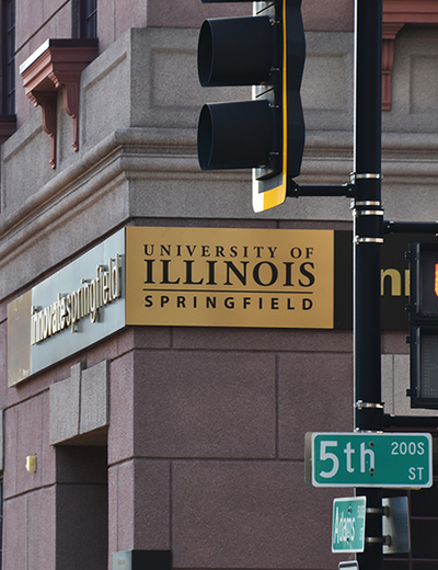 A building with a sign reading University of Illinois Springfield and a traffic light.