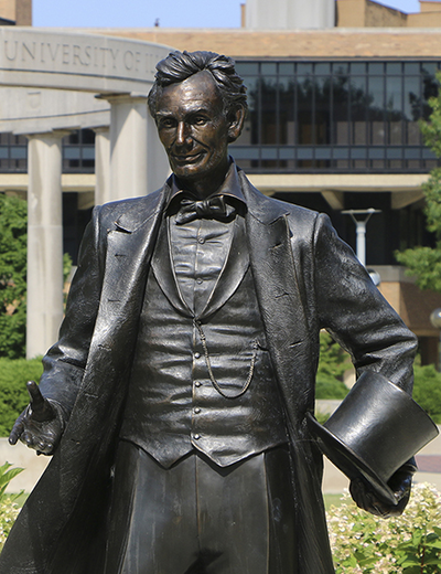 Statue of Abraham Lincoln with the UIS colonnade in the background.