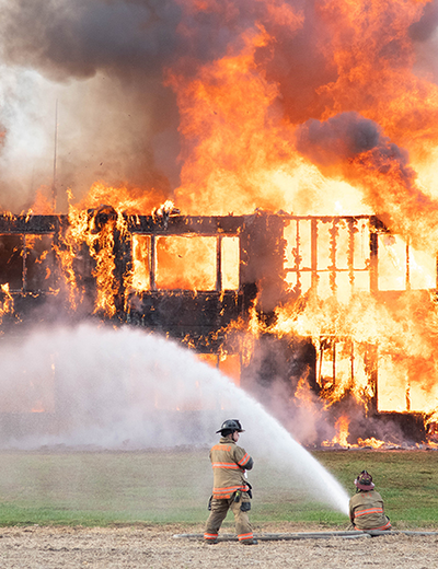Firefighters extinguishing a large building fire with hoses.