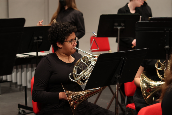 photograph of a woman playing a french horn 