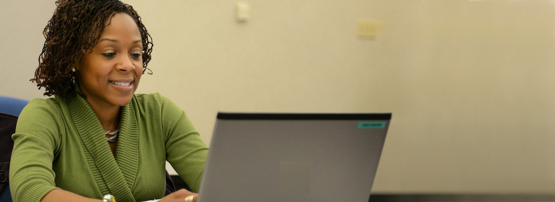 student smiling while looking at her laptop