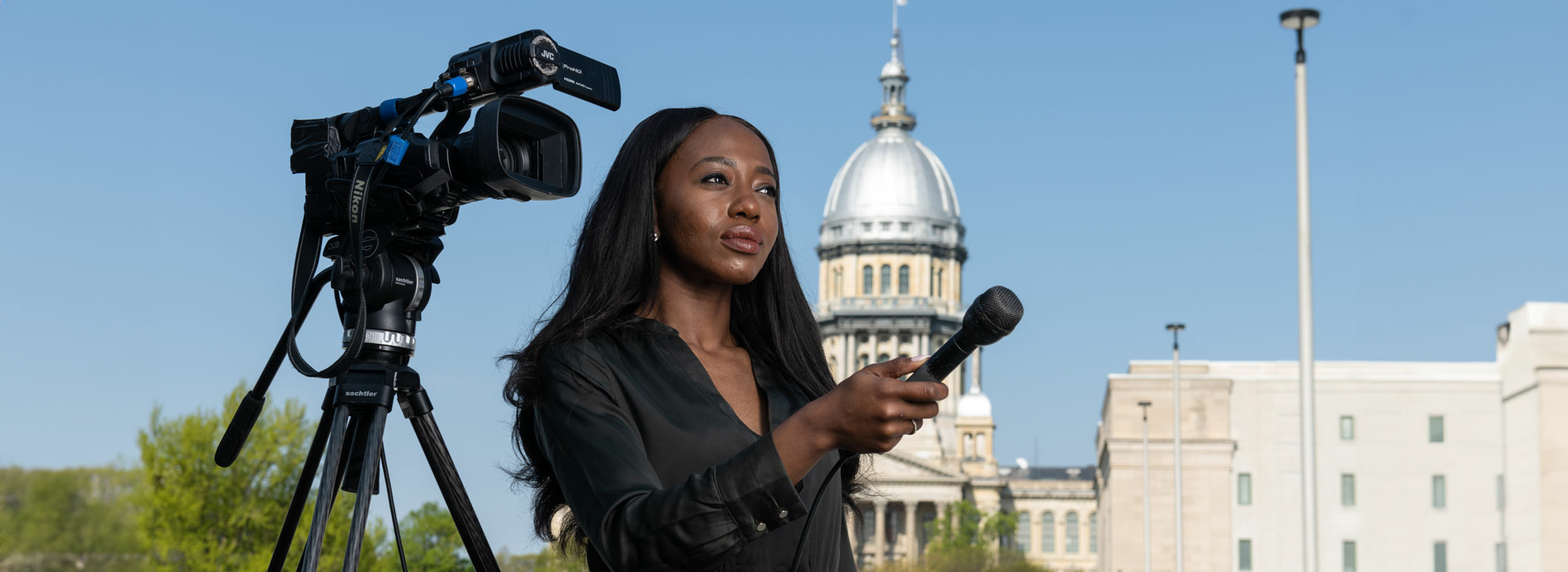 a student interviewing someone offscreen with a microphone and camera