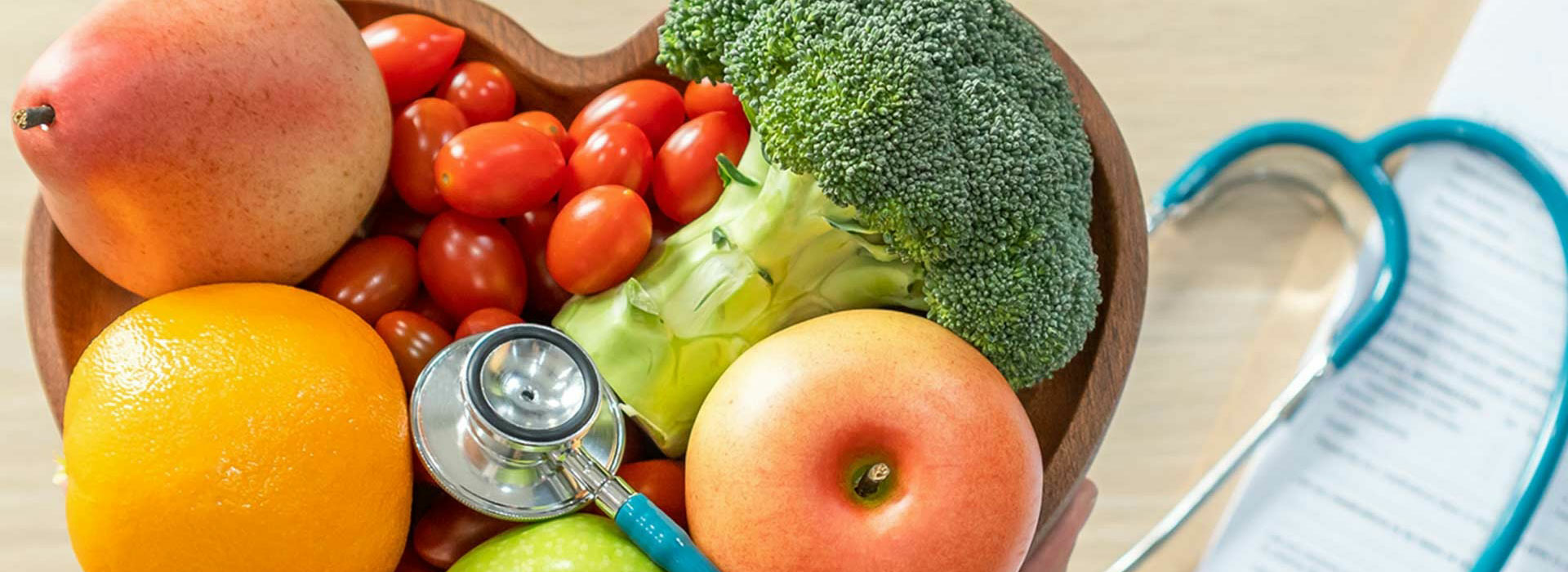 a stethoscope laying on top of a heart shaped bowl full of fruits and vegetables