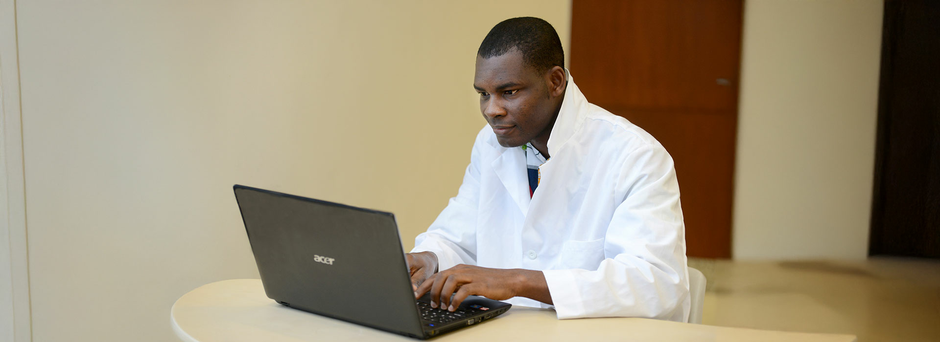 student in lab coat at computer